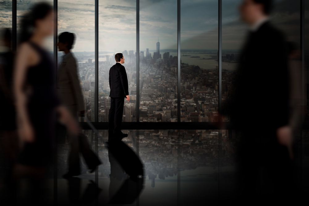 Businessman standing against room with large window looking on city