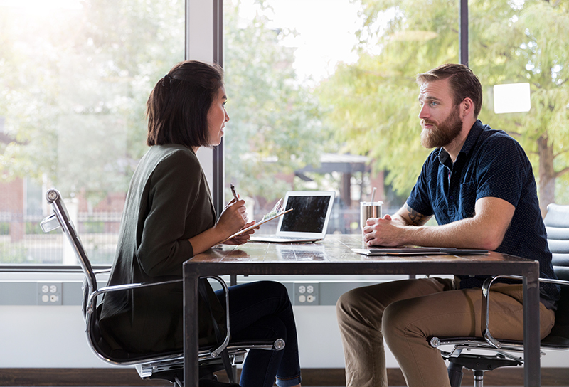 Encouraging female therapist discusses something with a male client. The client attentively listens to the therapist