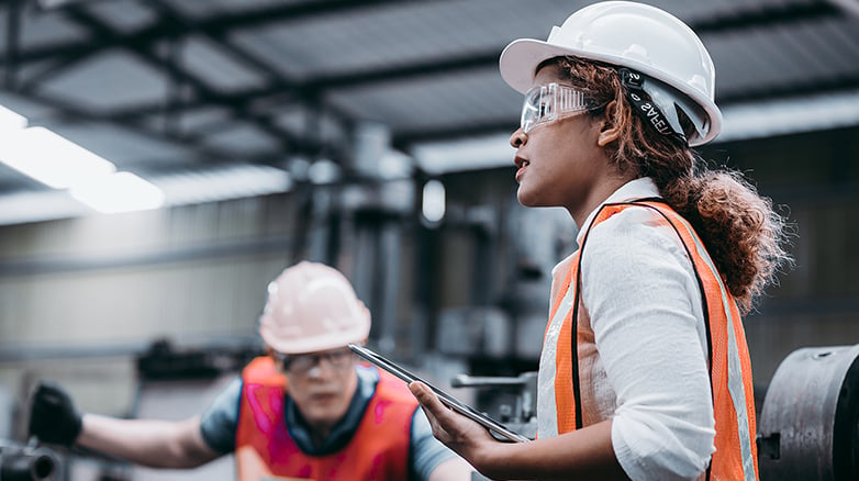 Woman working in a factory with a hard hat on
