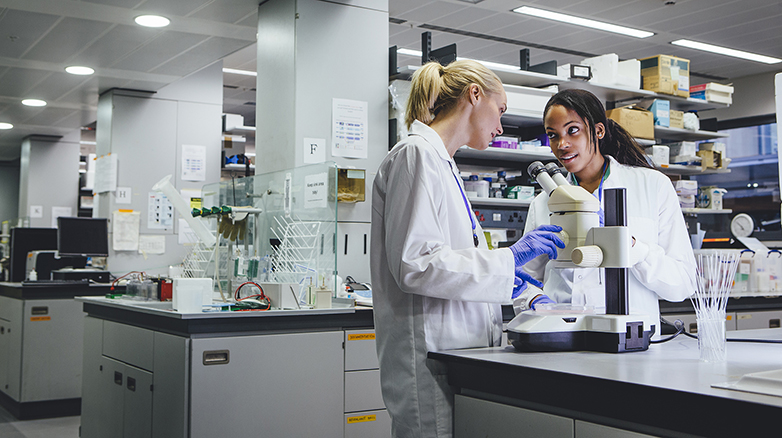 Two female scientists using a microscope in a laboratory