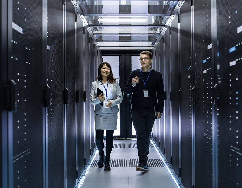 Two people walking through a server room