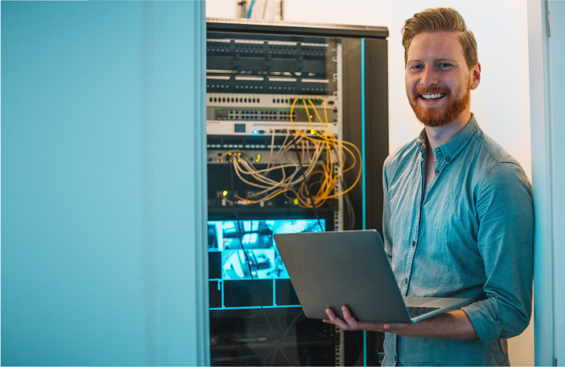 Male IT technician using laptop in server room
